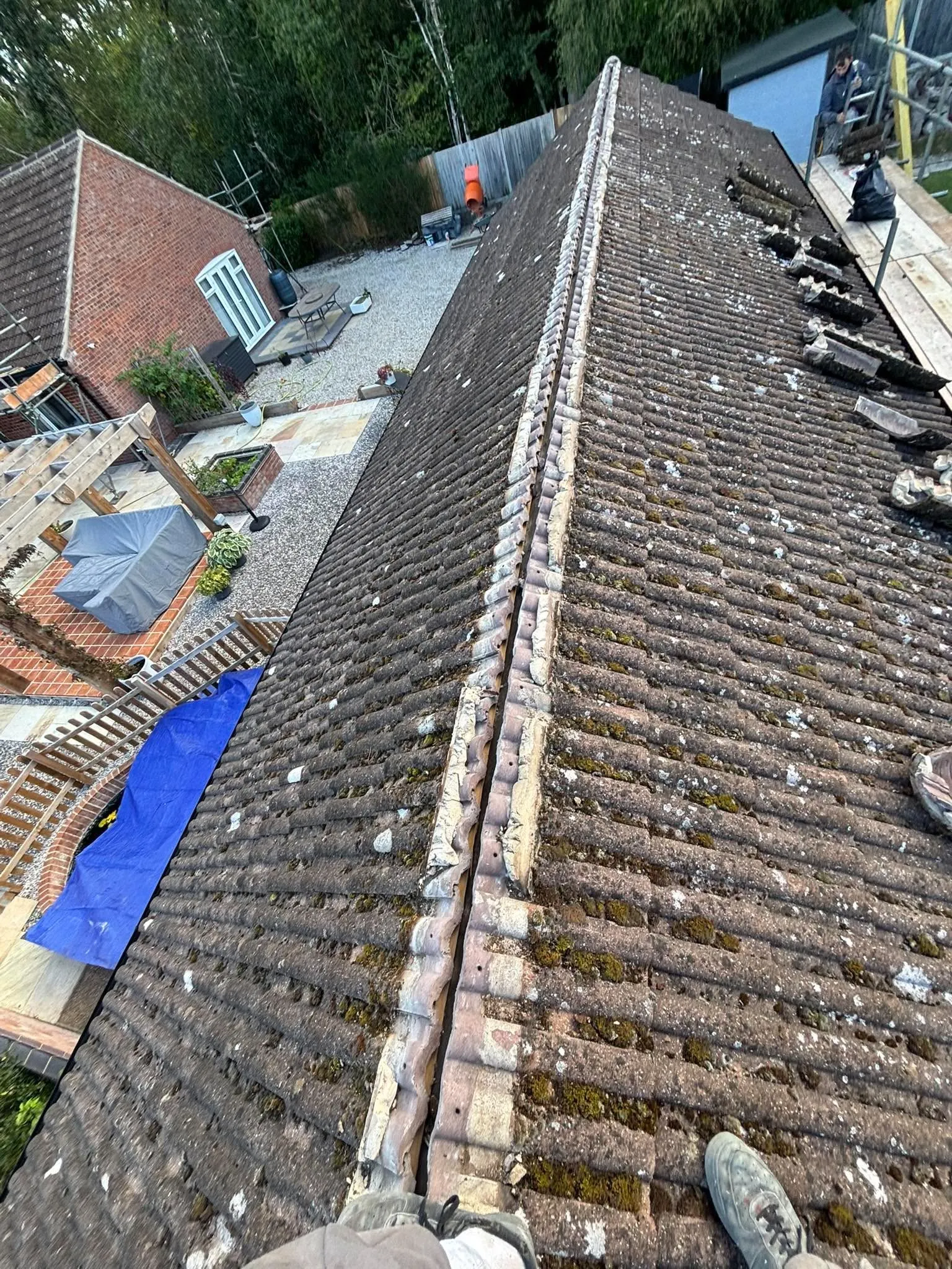Pitched tiled roof undergoing ridge repair work
